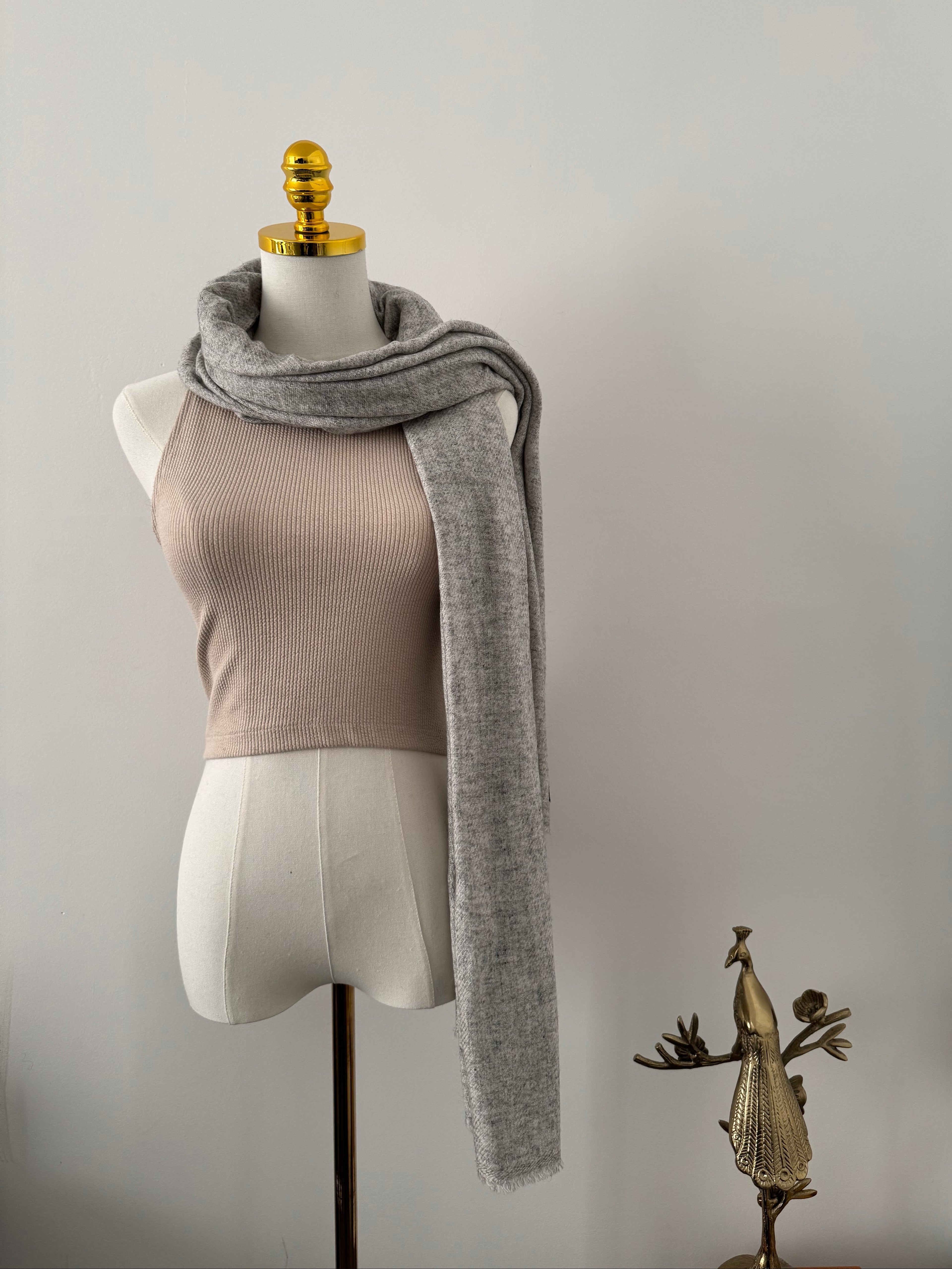 Mannequin wearing a gray scarf on a plain background