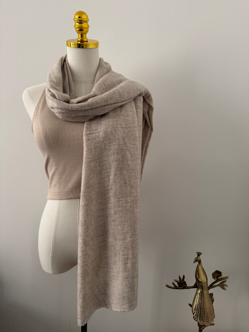 Mannequin wearing a beige scarf on a plain background