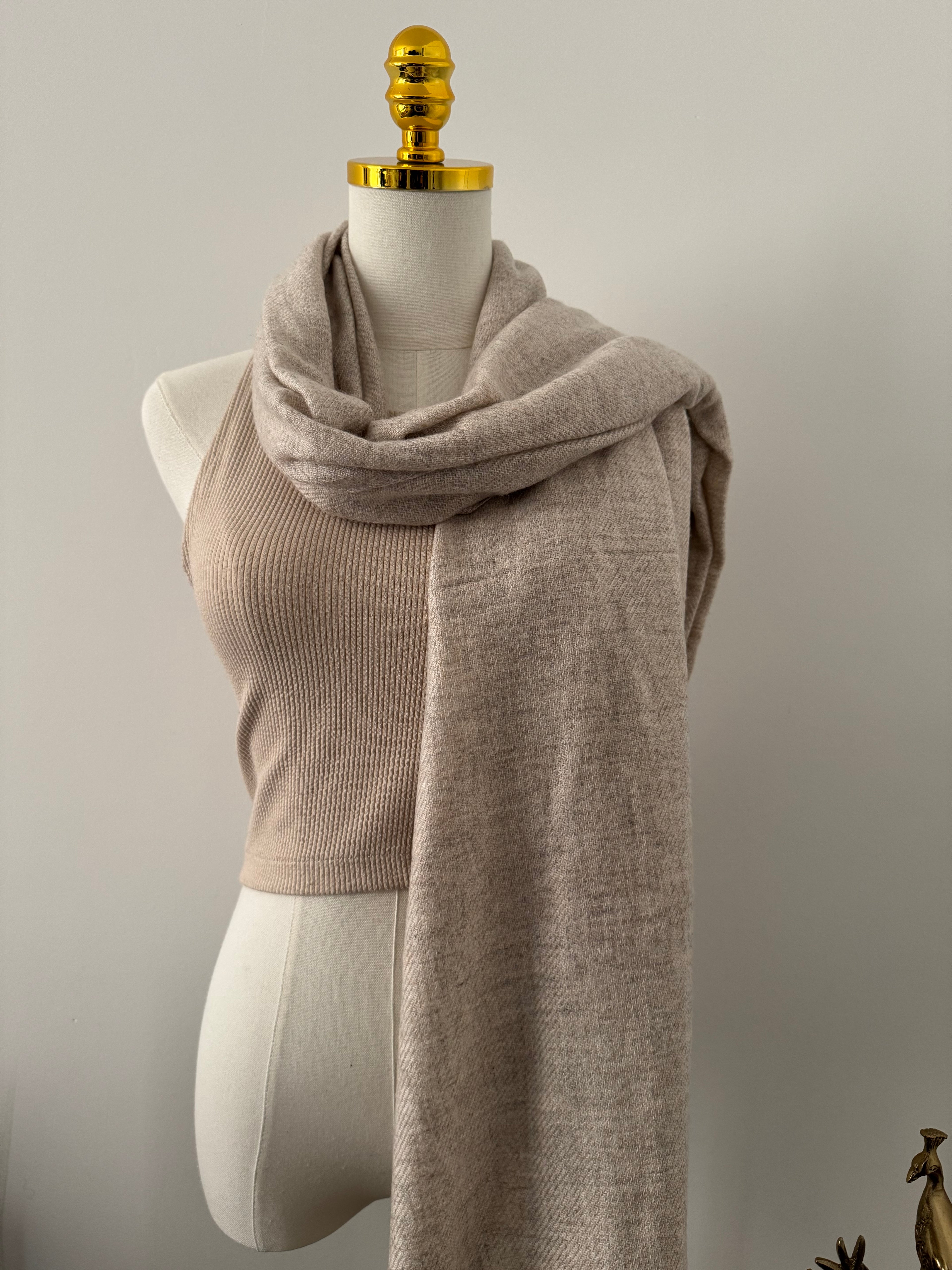 Decorative beige fabric shawl on a plain background