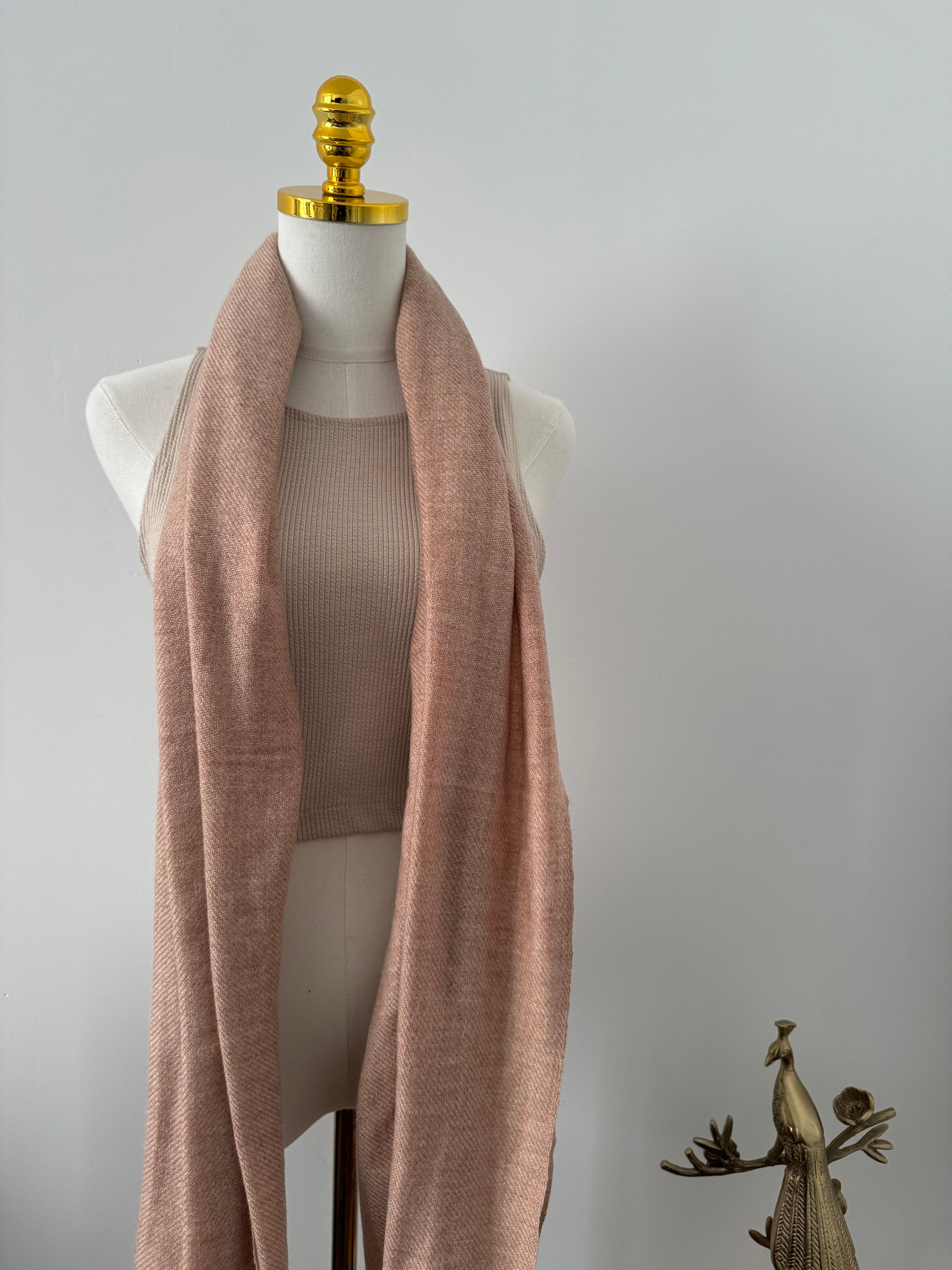 Mannequin wearing a light brown fabric on a plain background