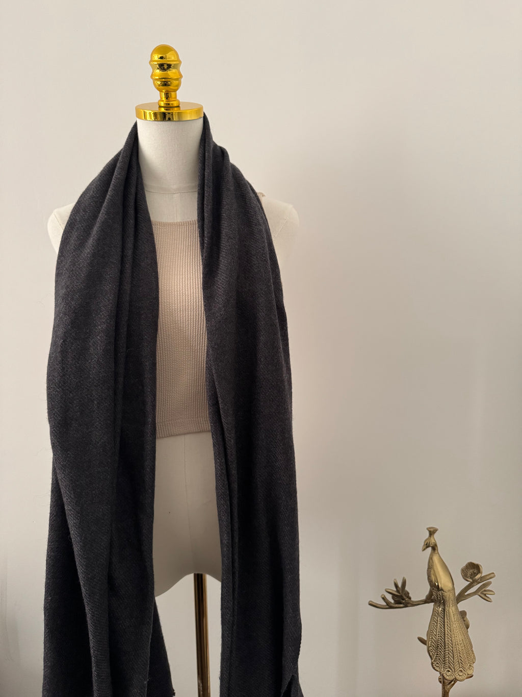 Mannequin wearing a black garment with gold accents on a plain background