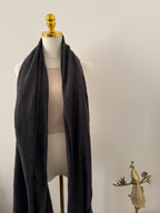 Mannequin wearing a black garment with gold accents on a plain background