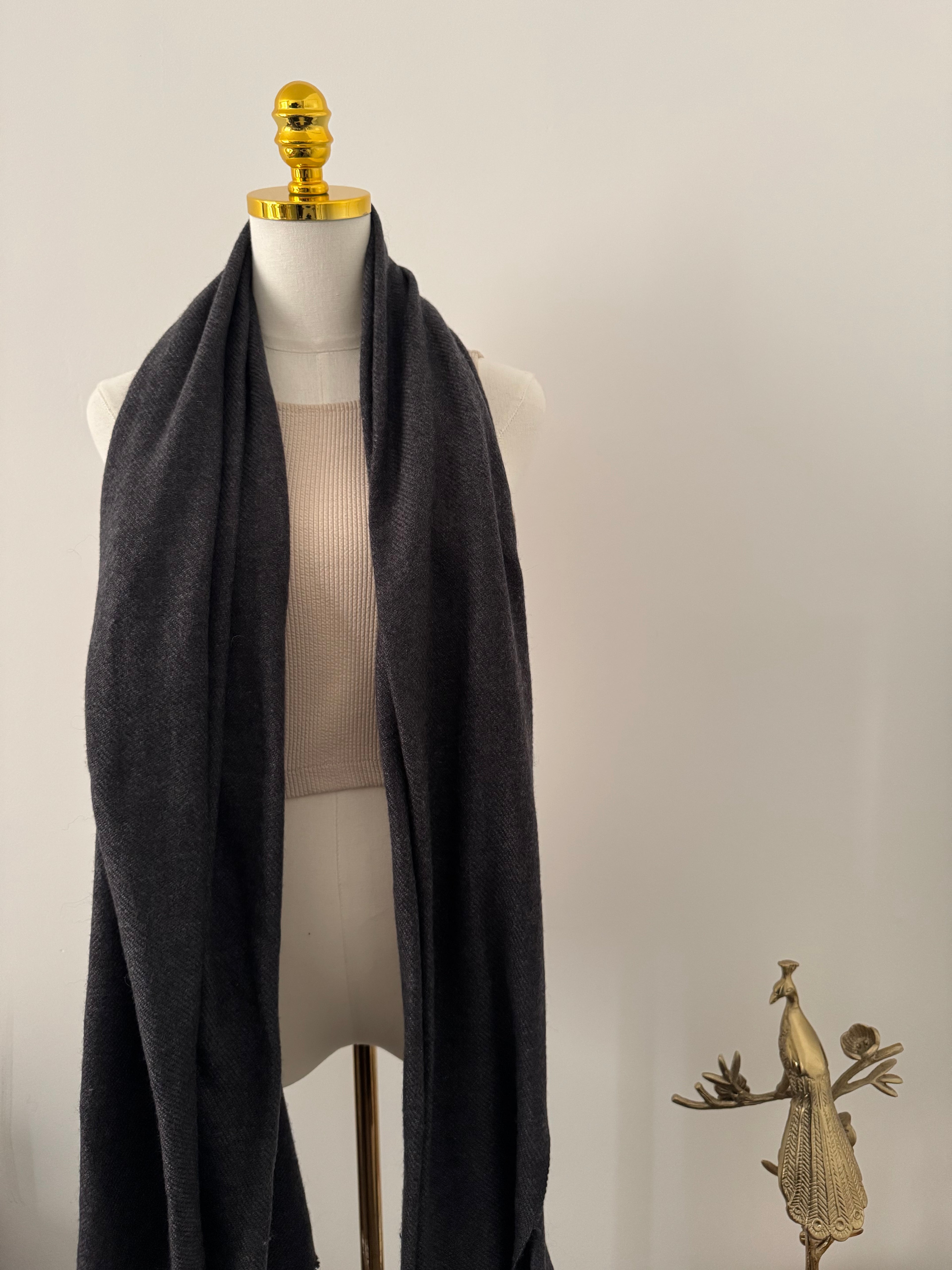 Mannequin wearing a black garment with gold accents on a plain background