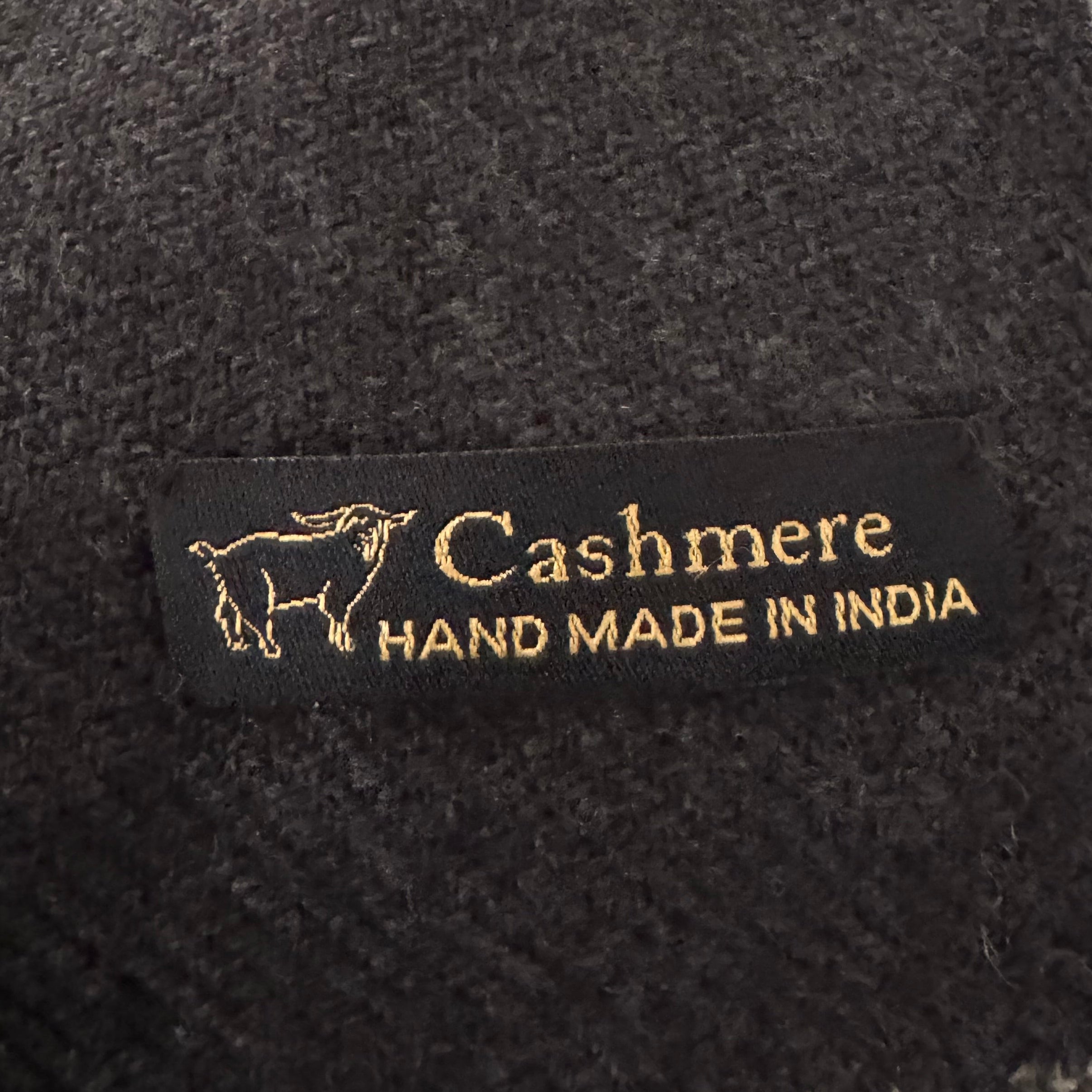 Label on dark fabric indicating 'Cashmere Hand Made in India'.