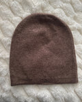 Brown knitted beanie on a textured white surface