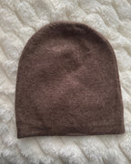 Brown knitted beanie on a textured white surface