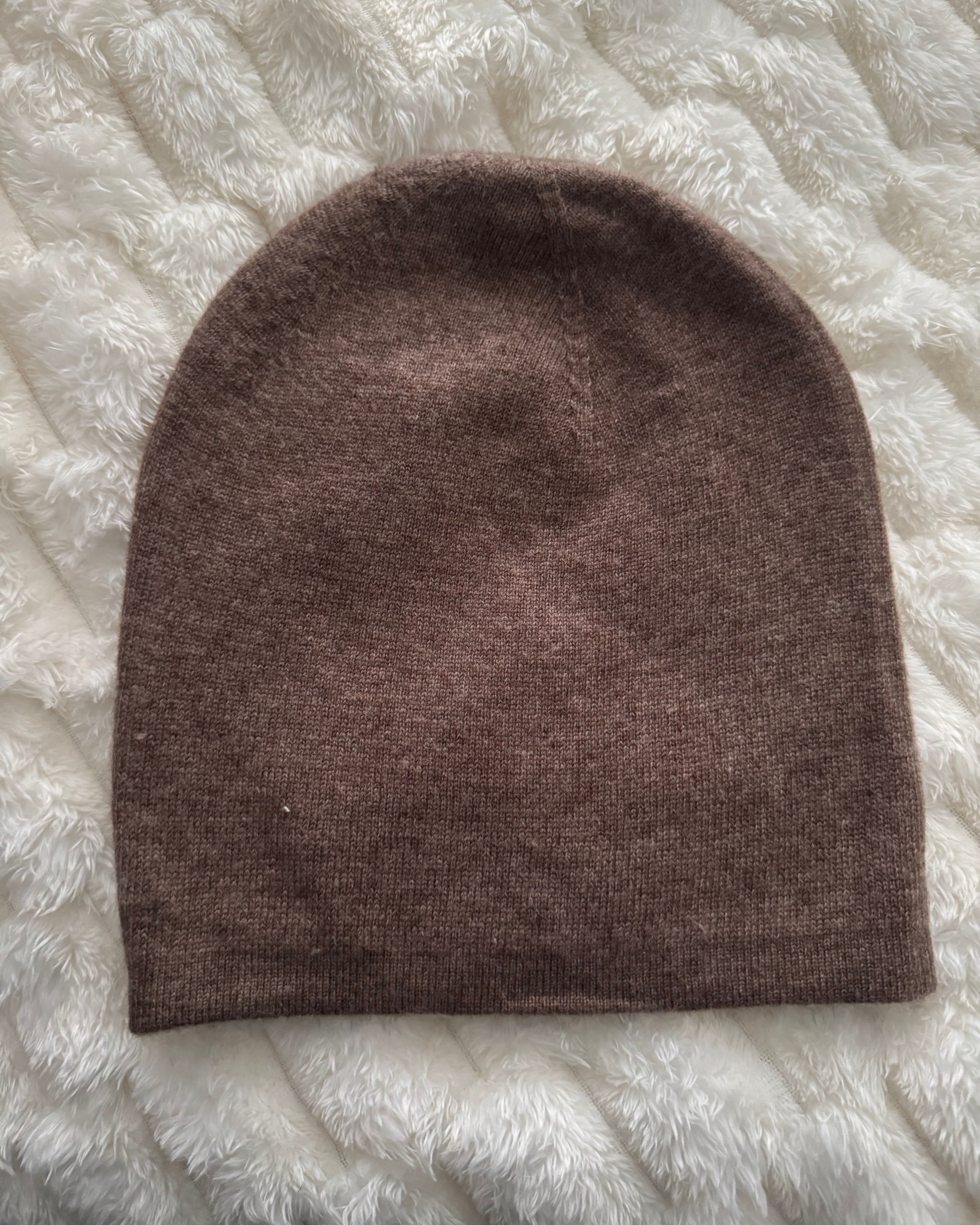 Brown knitted beanie on a textured white surface