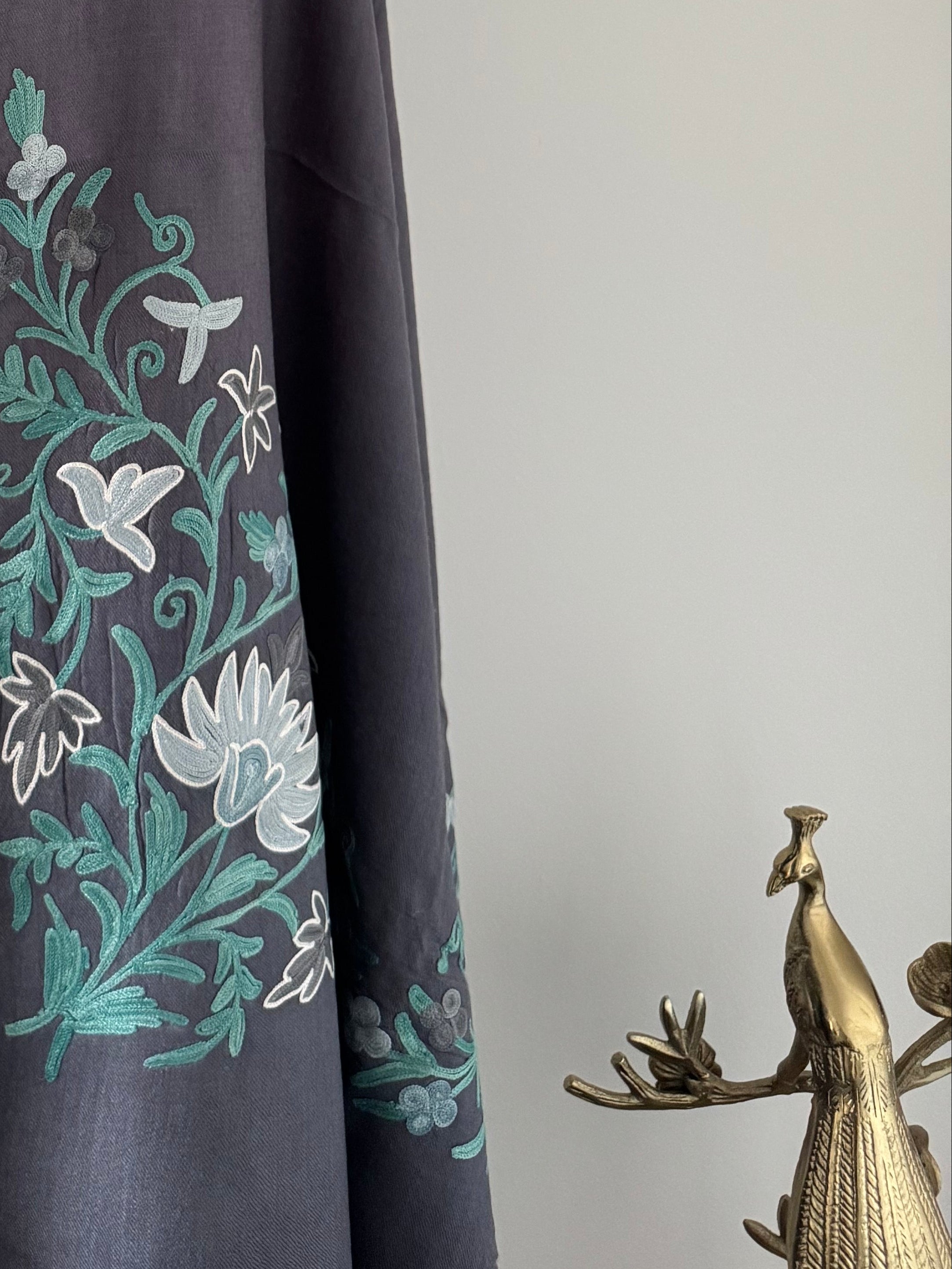 Gray fabric with green floral embroidery on a mannequin against a white background