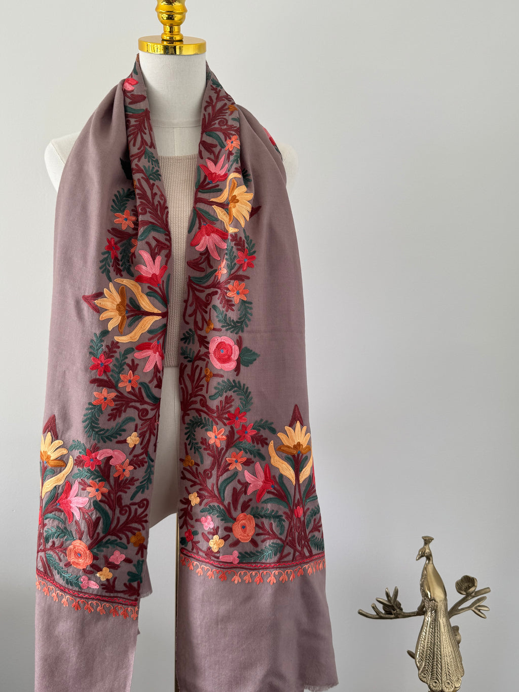 Decorative fabric with floral embroidery on a mannequin against a plain background