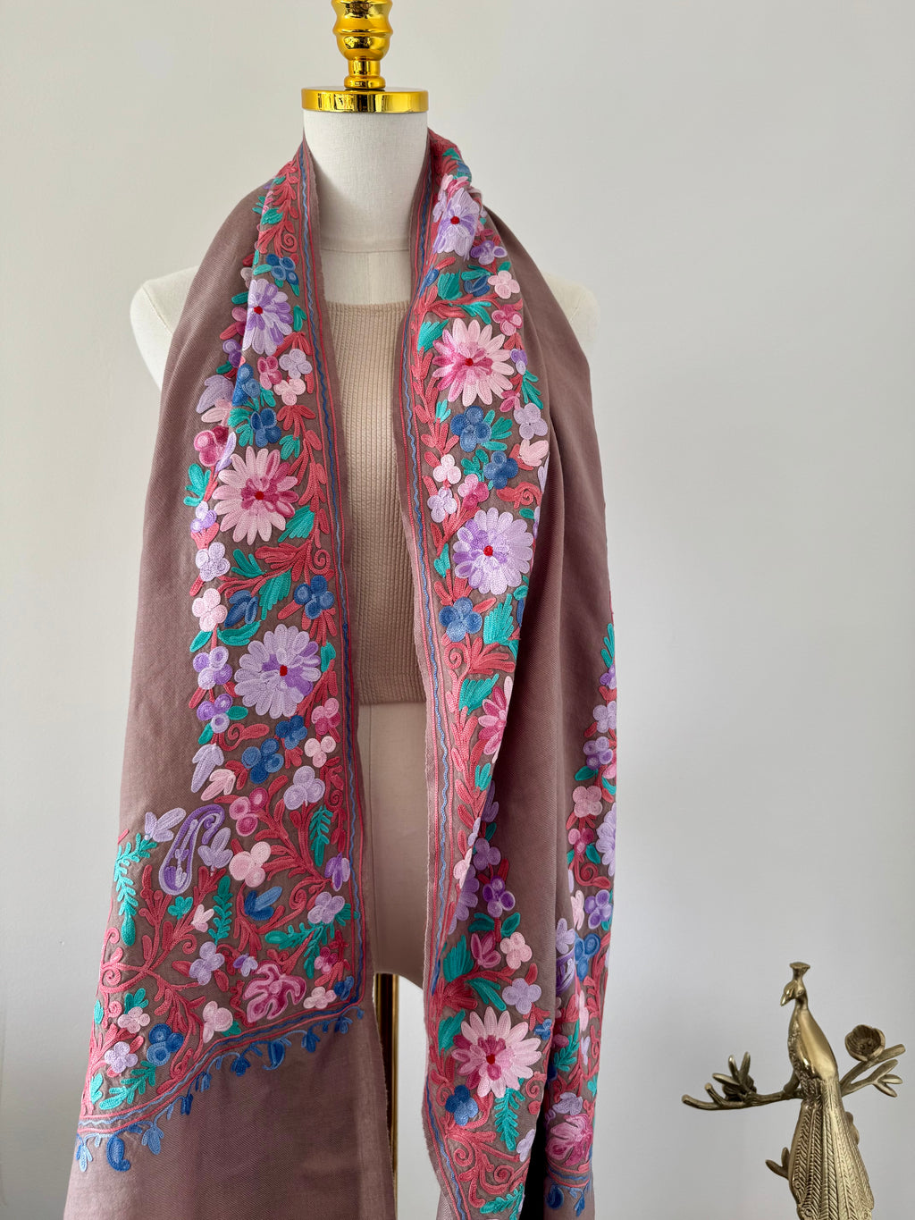 Floral embroidered scarf on a mannequin against a plain background