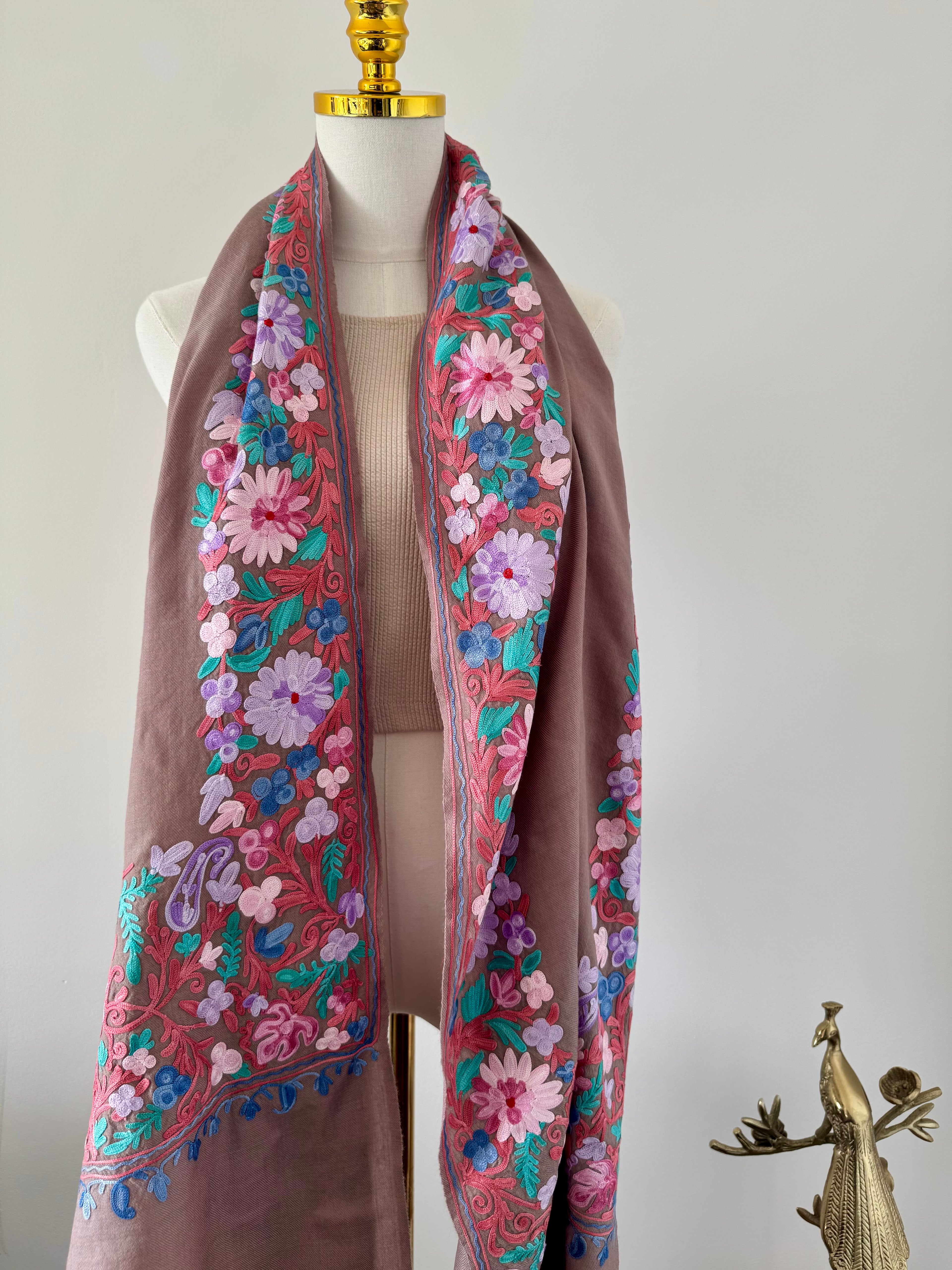 Floral embroidered scarf on a mannequin against a plain background