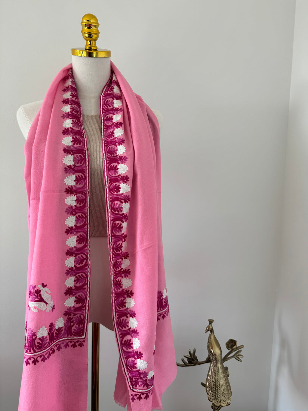 Pink shawl with white embroidery on a white background