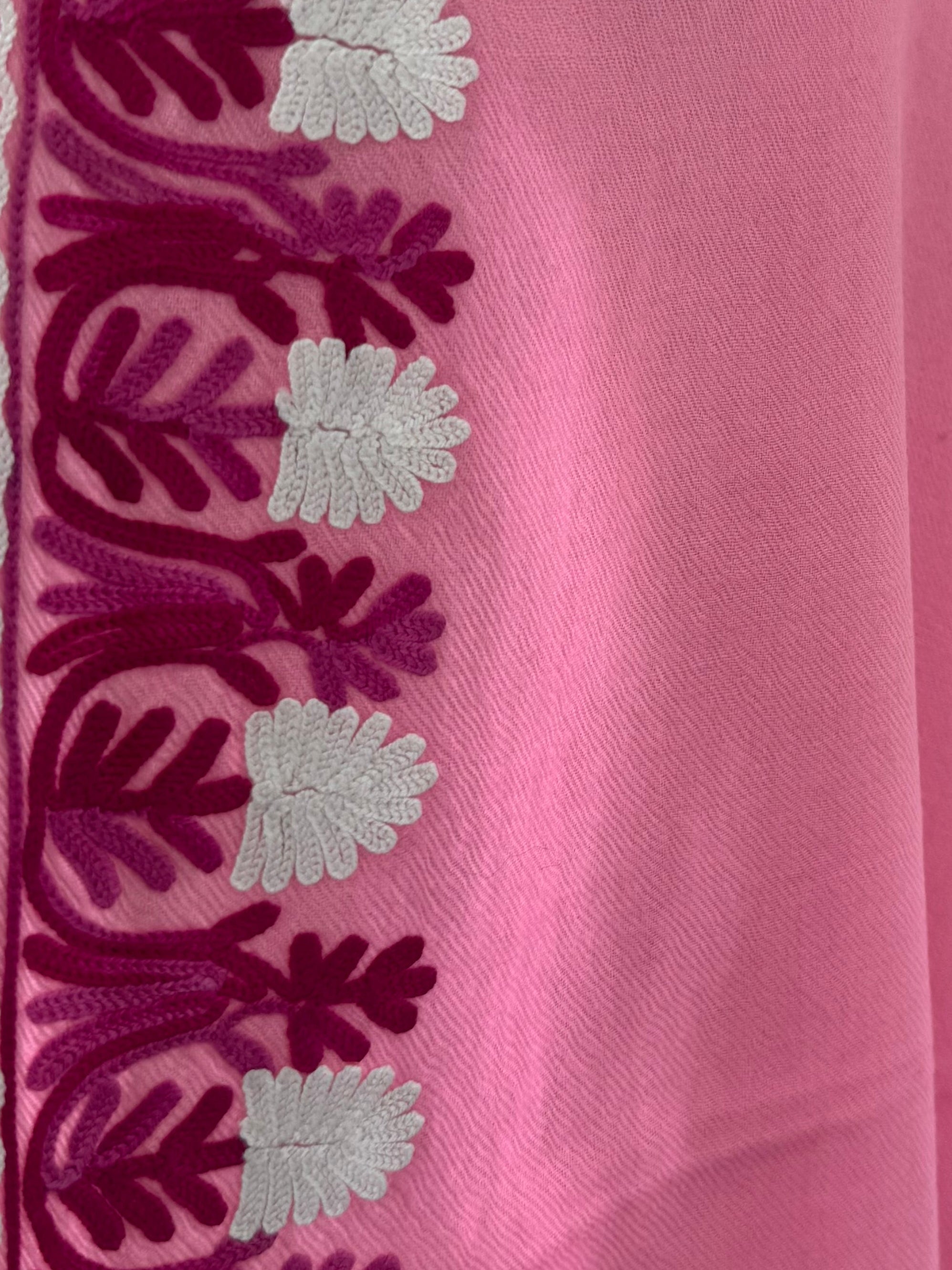 Pink fabric with embroidered border on a white background