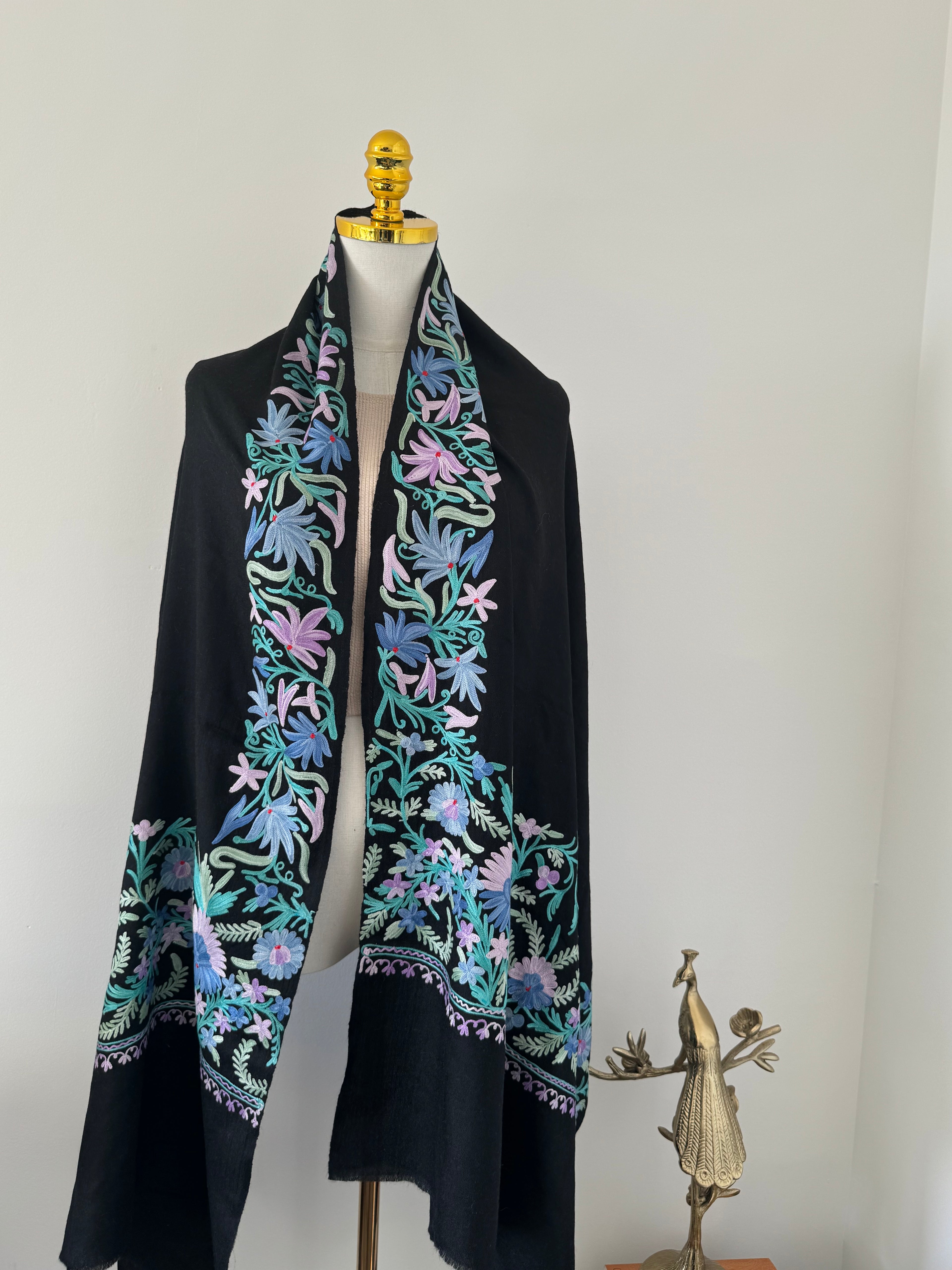 Black shawl with colorful floral embroidery on a white background