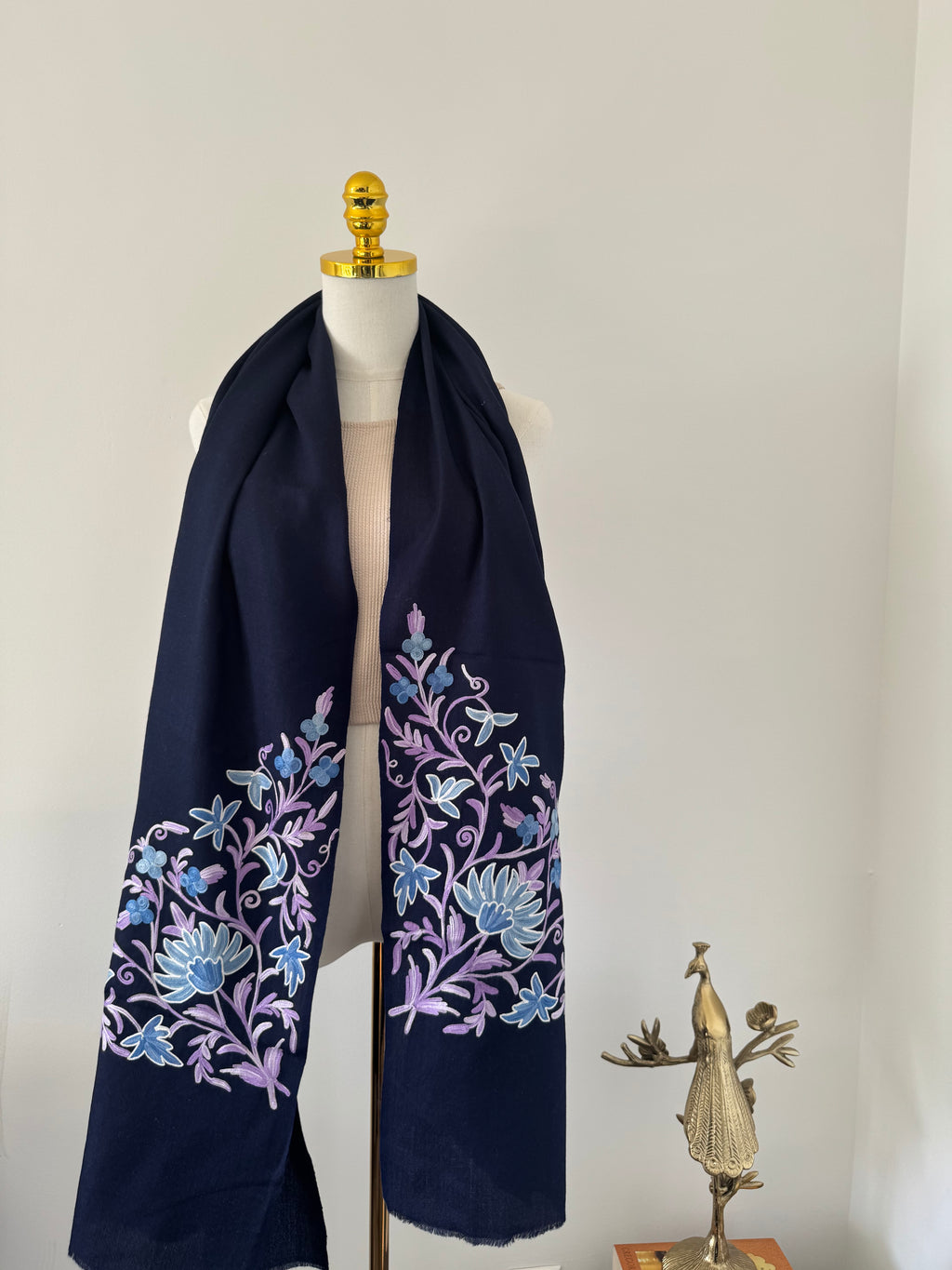 Navy blue shawl with floral embroidery on a mannequin against a neutral background
