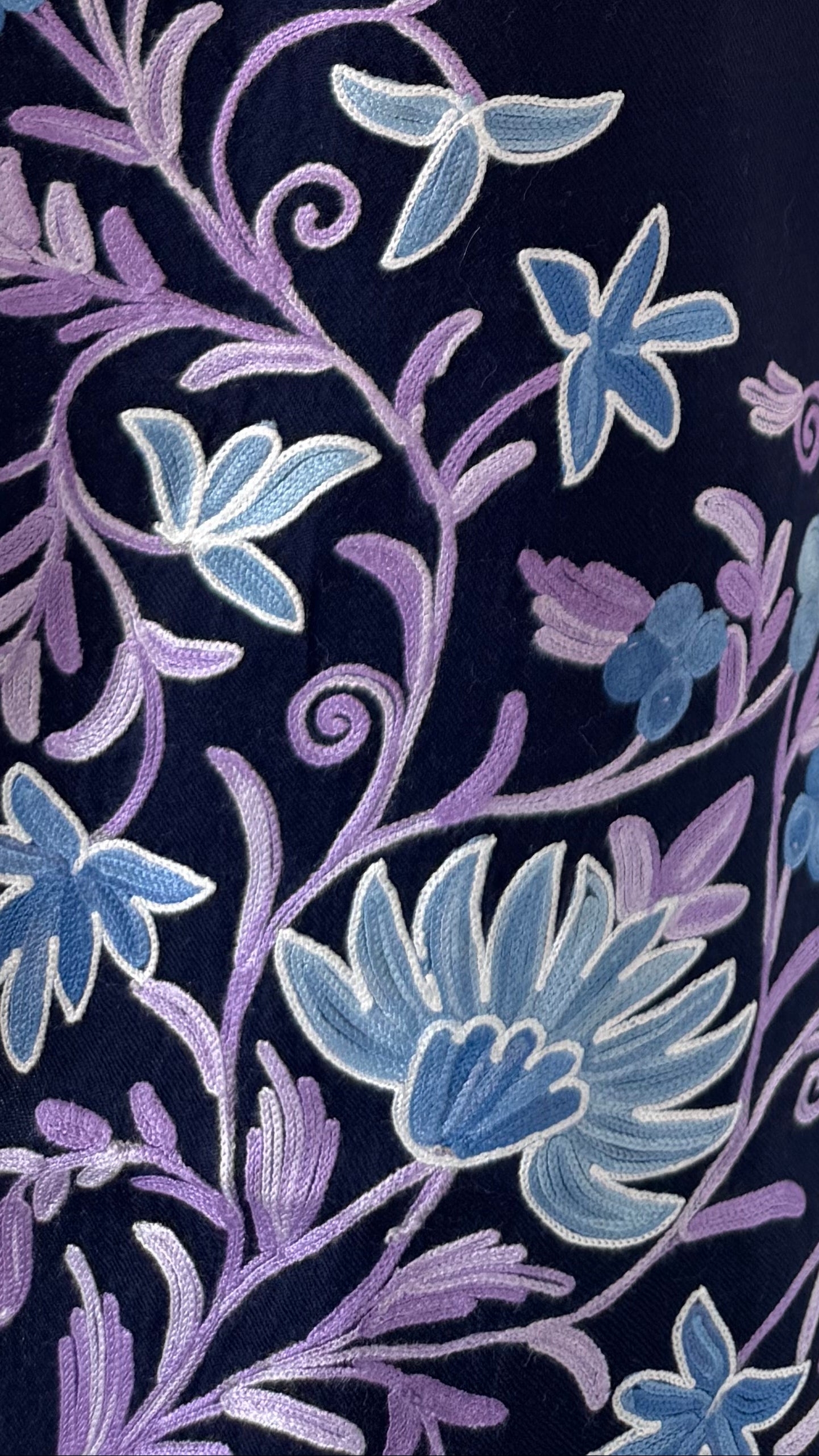 Close-up of floral embroidery with blue and purple flowers on a dark background