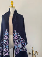 Navy blue fabric with floral embroidery on a mannequin against a neutral background