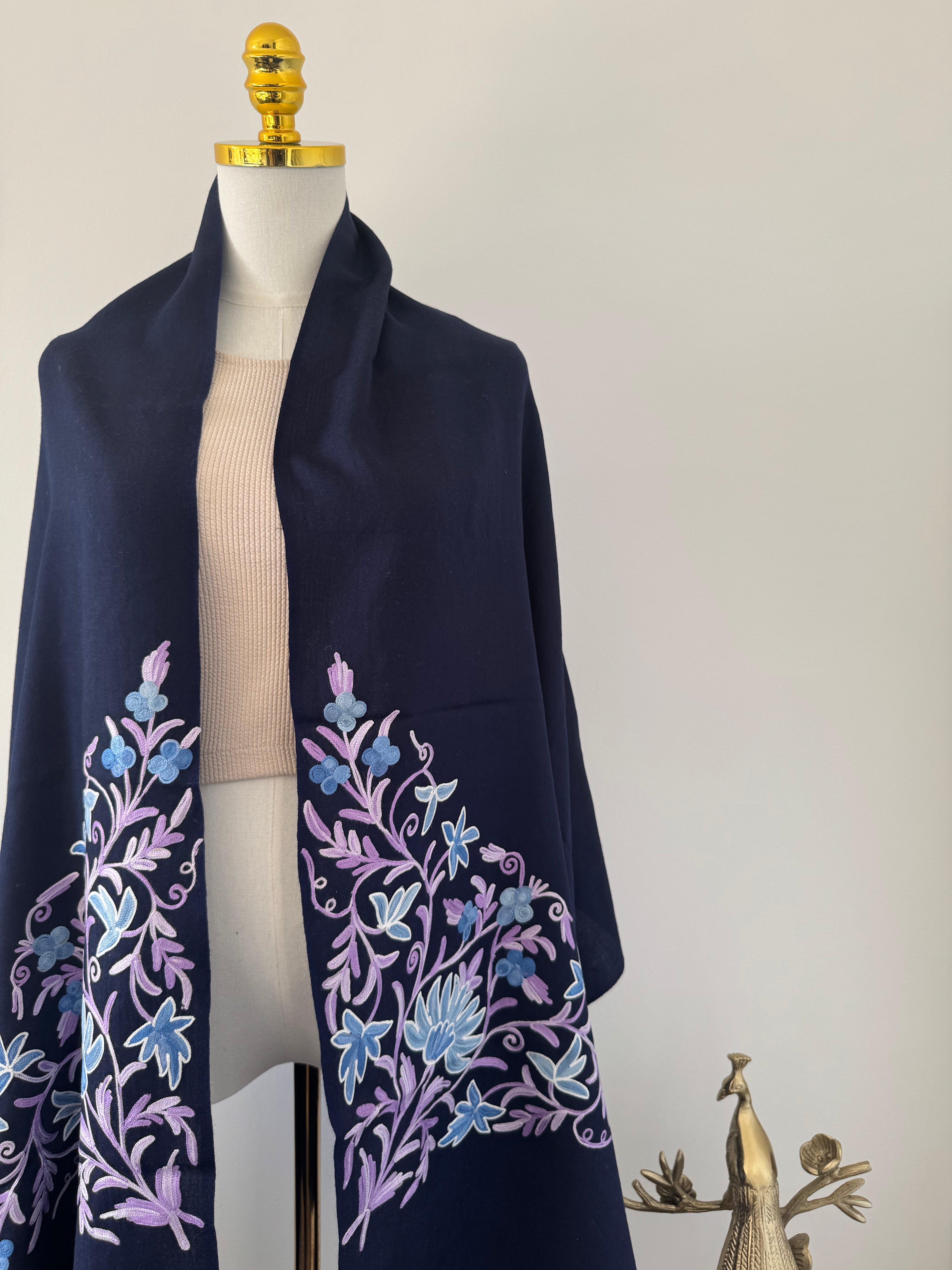 Navy blue fabric with floral embroidery on a mannequin against a neutral background