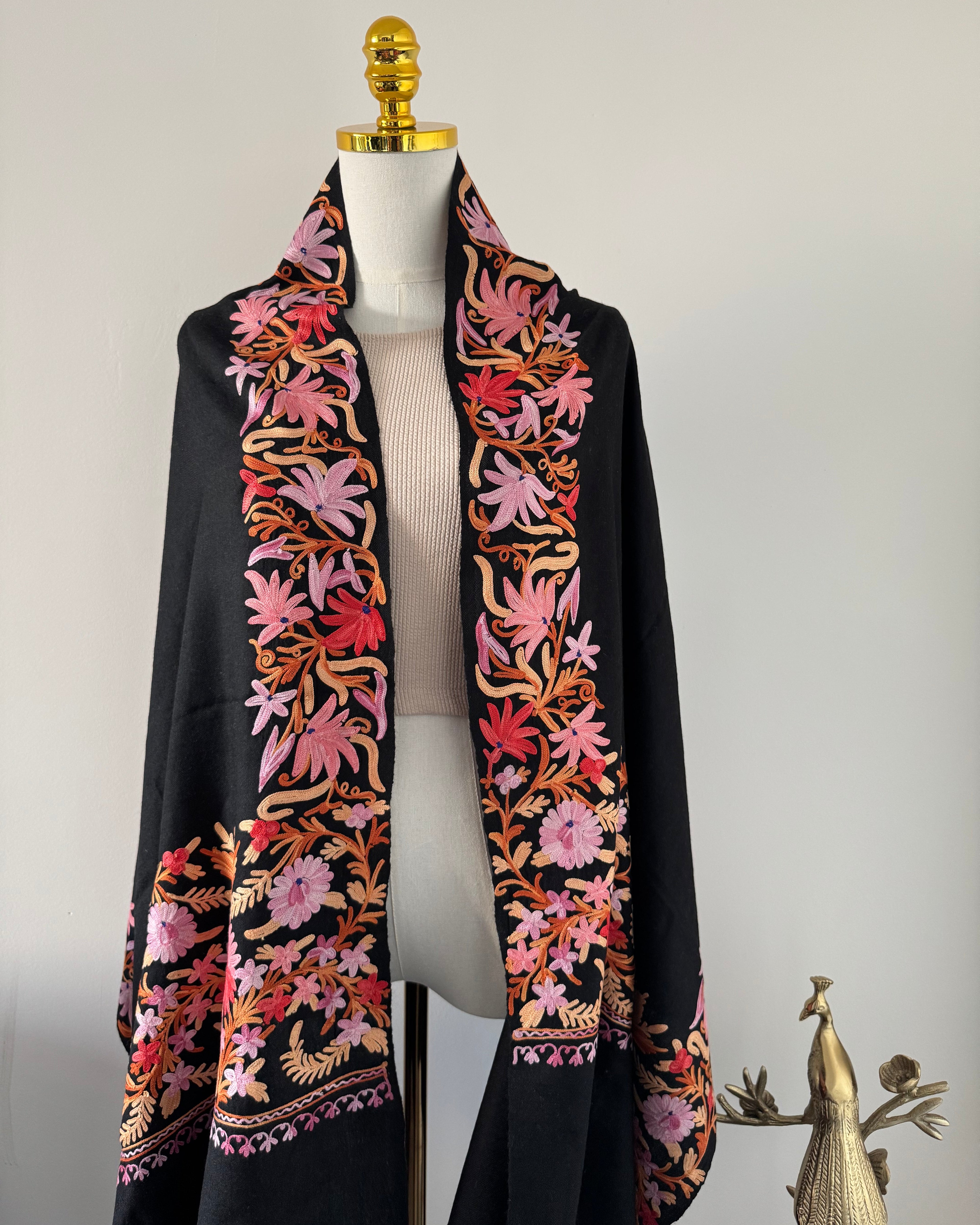 Decorative shawl with floral patterns on a mannequin head against a neutral background