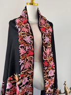Black fabric with colorful floral embroidery on a white background
