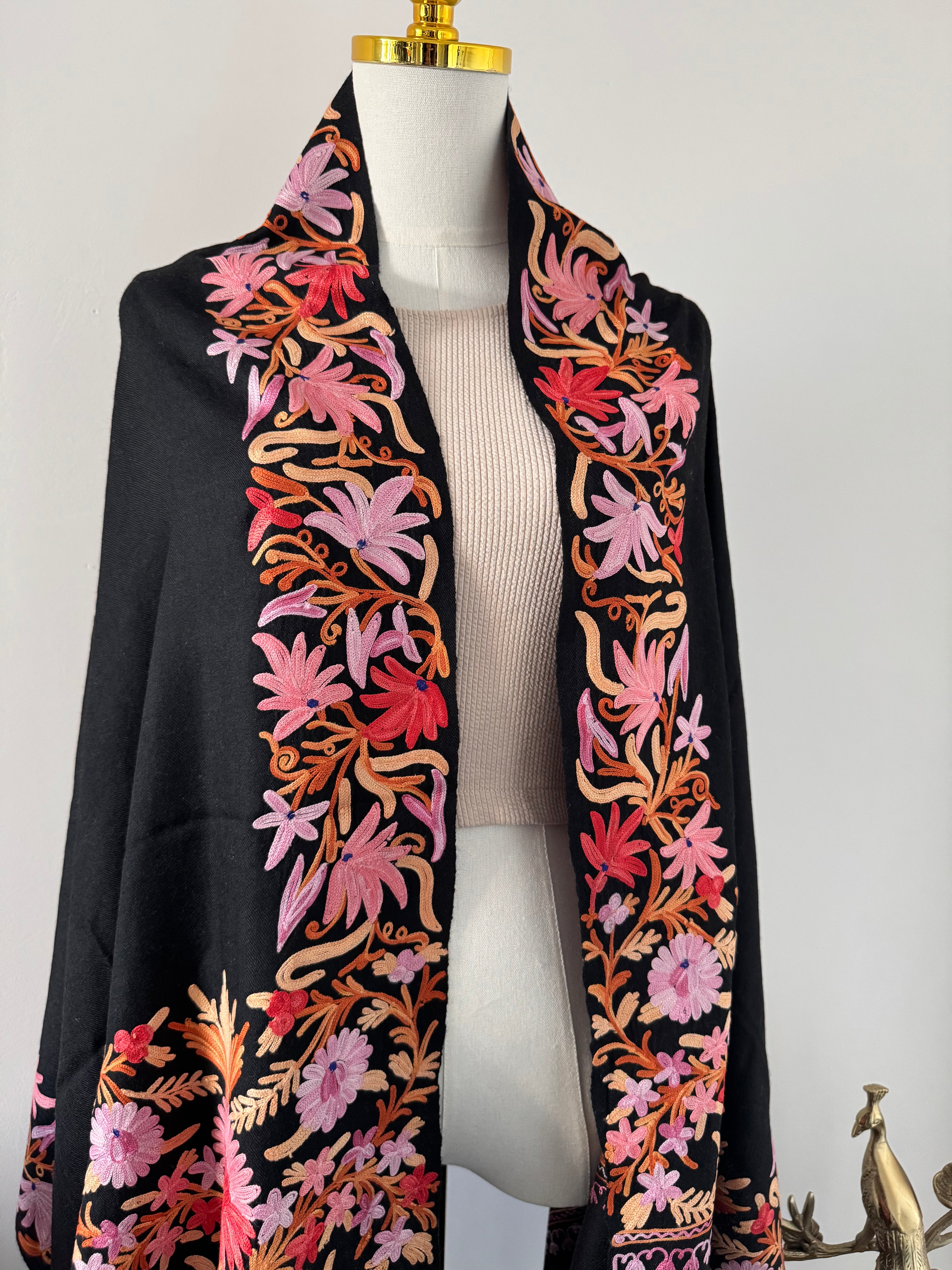 Black fabric with colorful floral embroidery on a white background