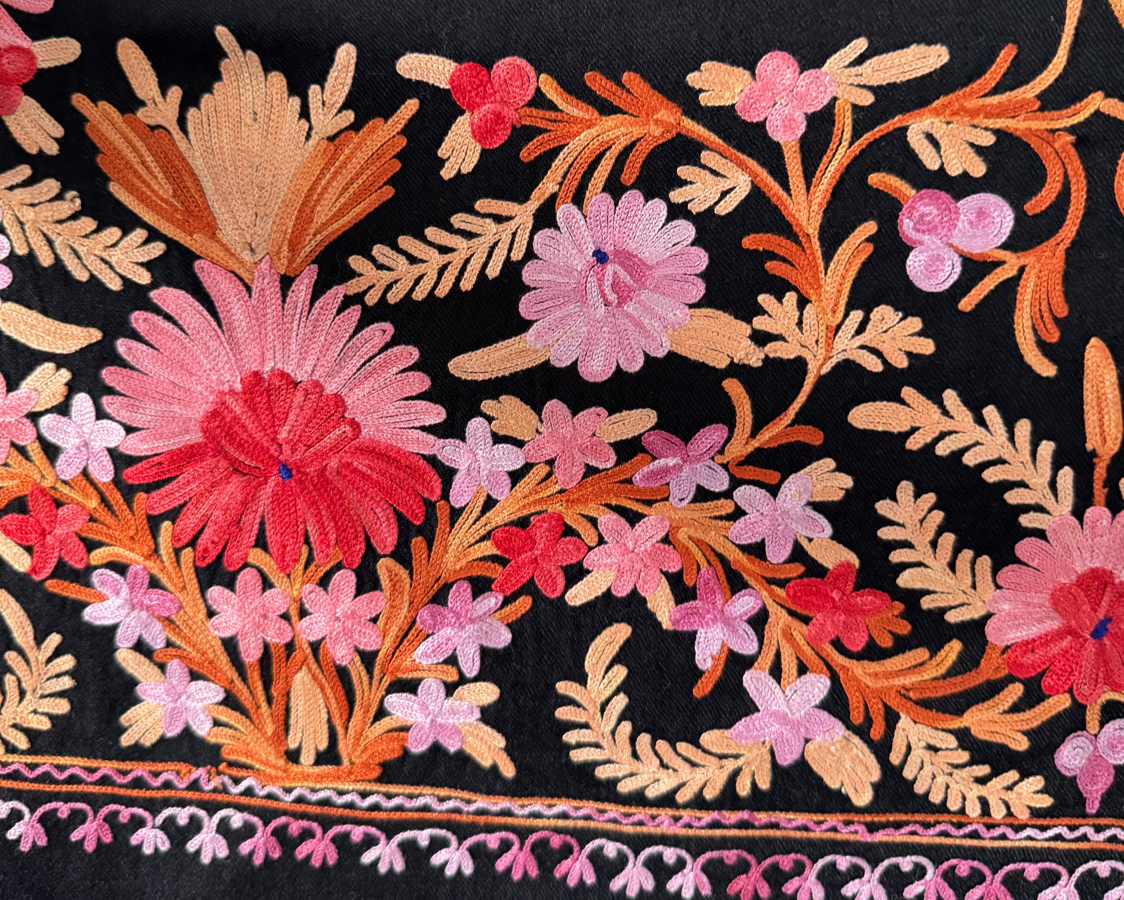 Black fabric with colorful floral embroidery on a white background