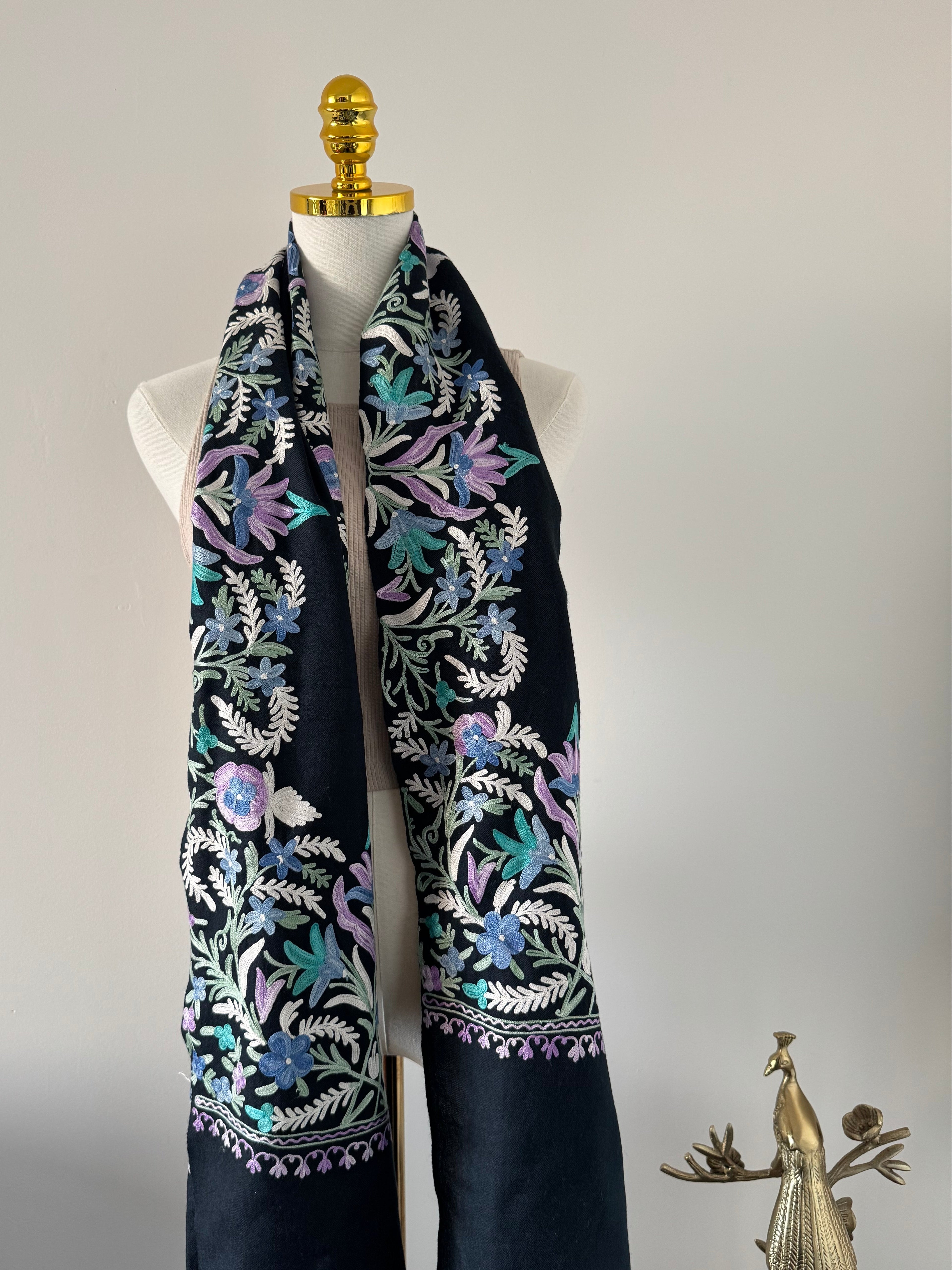 Embroidered fabric on a mannequin with floral patterns against a plain background