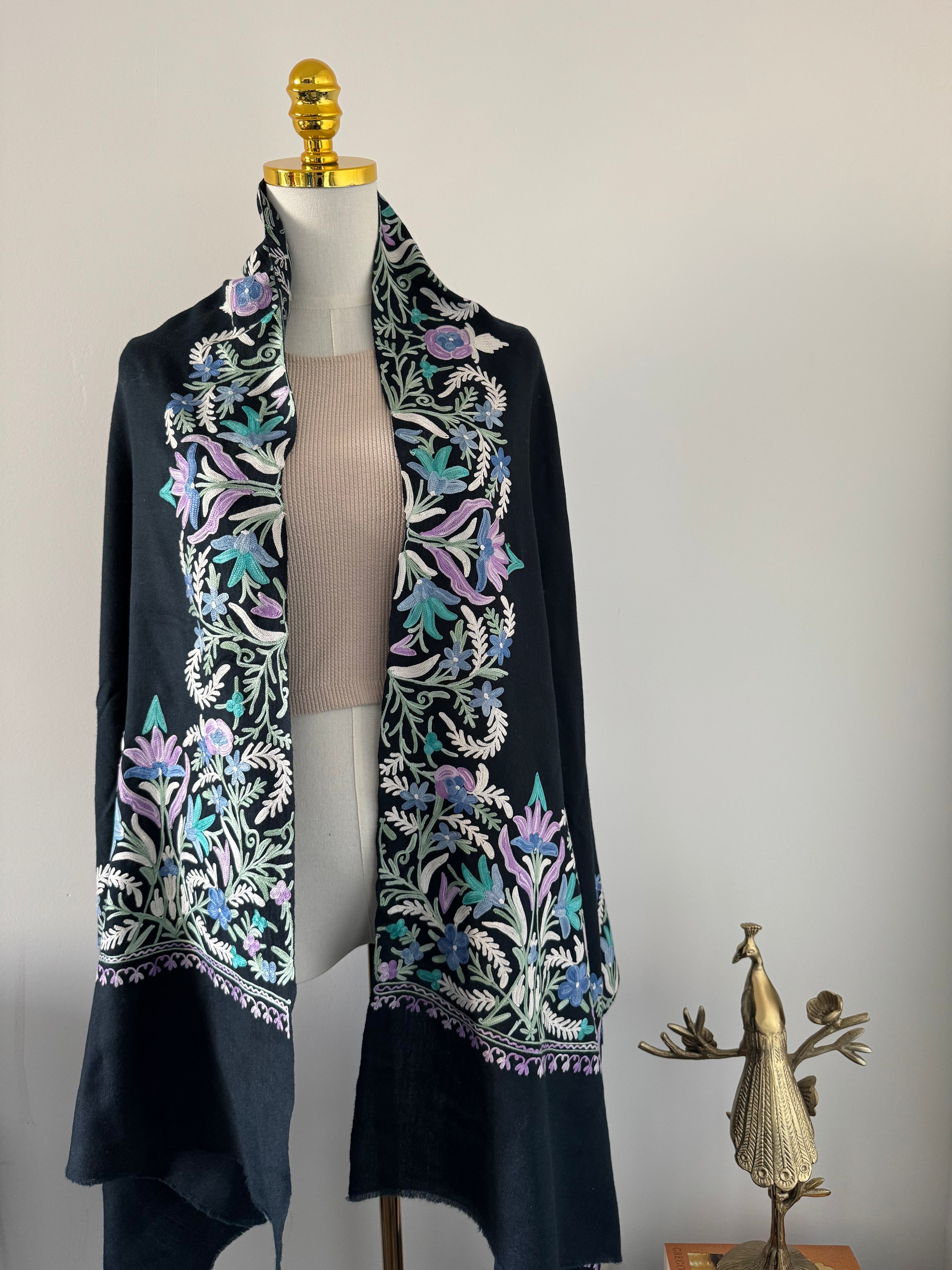 Navy blue fabric with intricate floral embroidery on a mannequin against a neutral background
