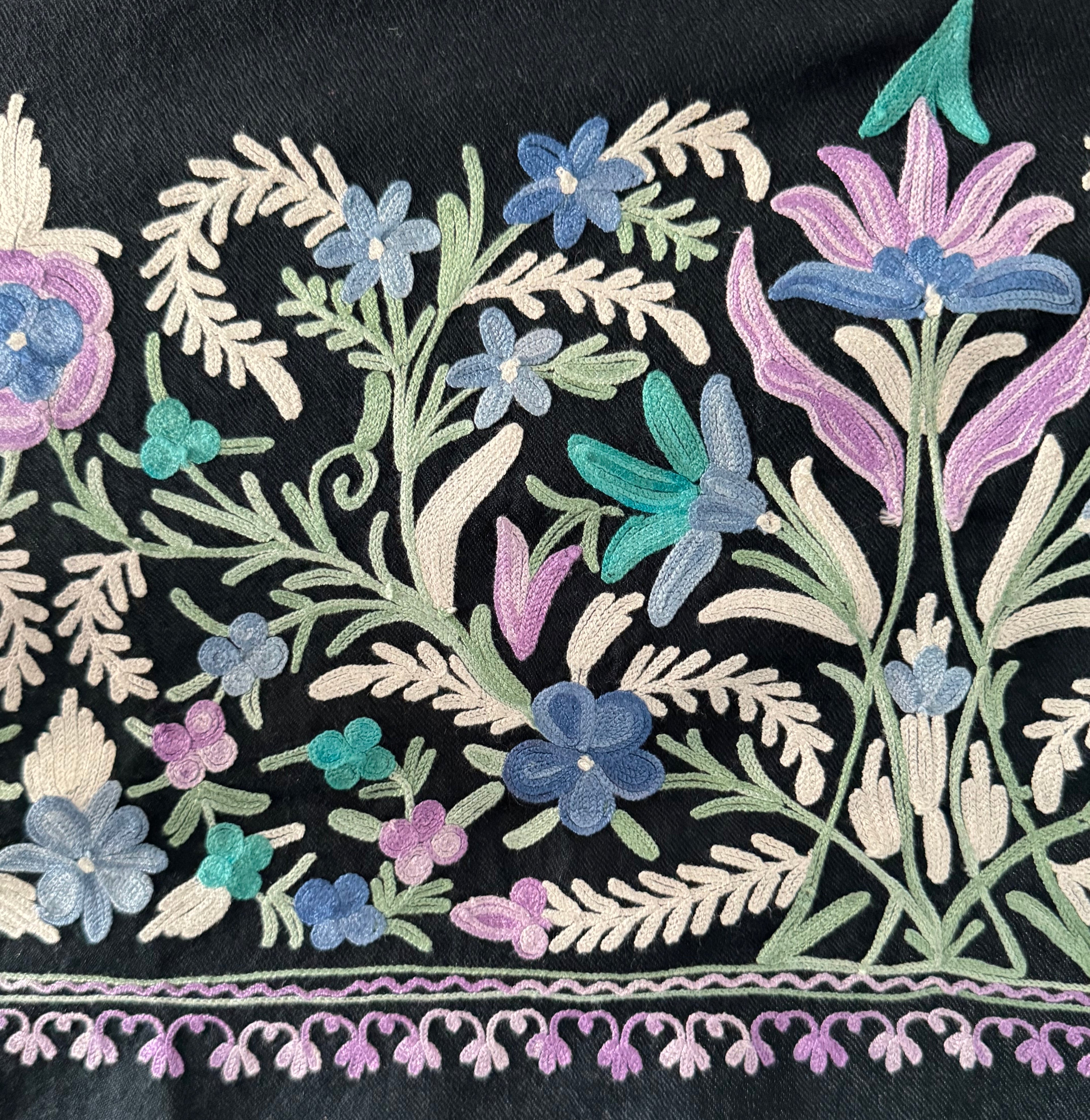 Close-up of embroidered floral design on a black fabric background