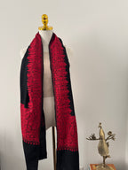 Red and black embroidered garment on a mannequin against a plain background