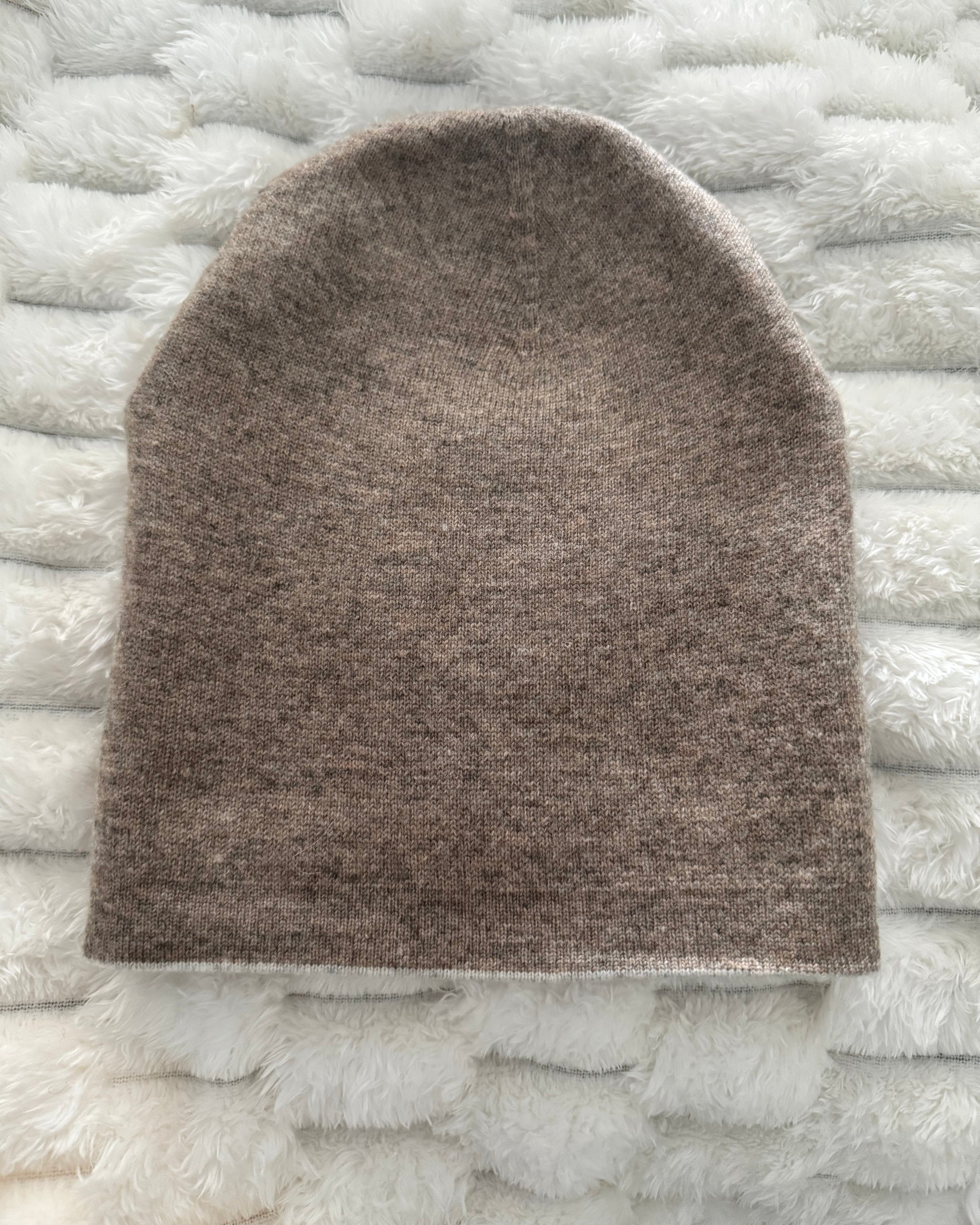 Brown knitted beanie on a textured white surface