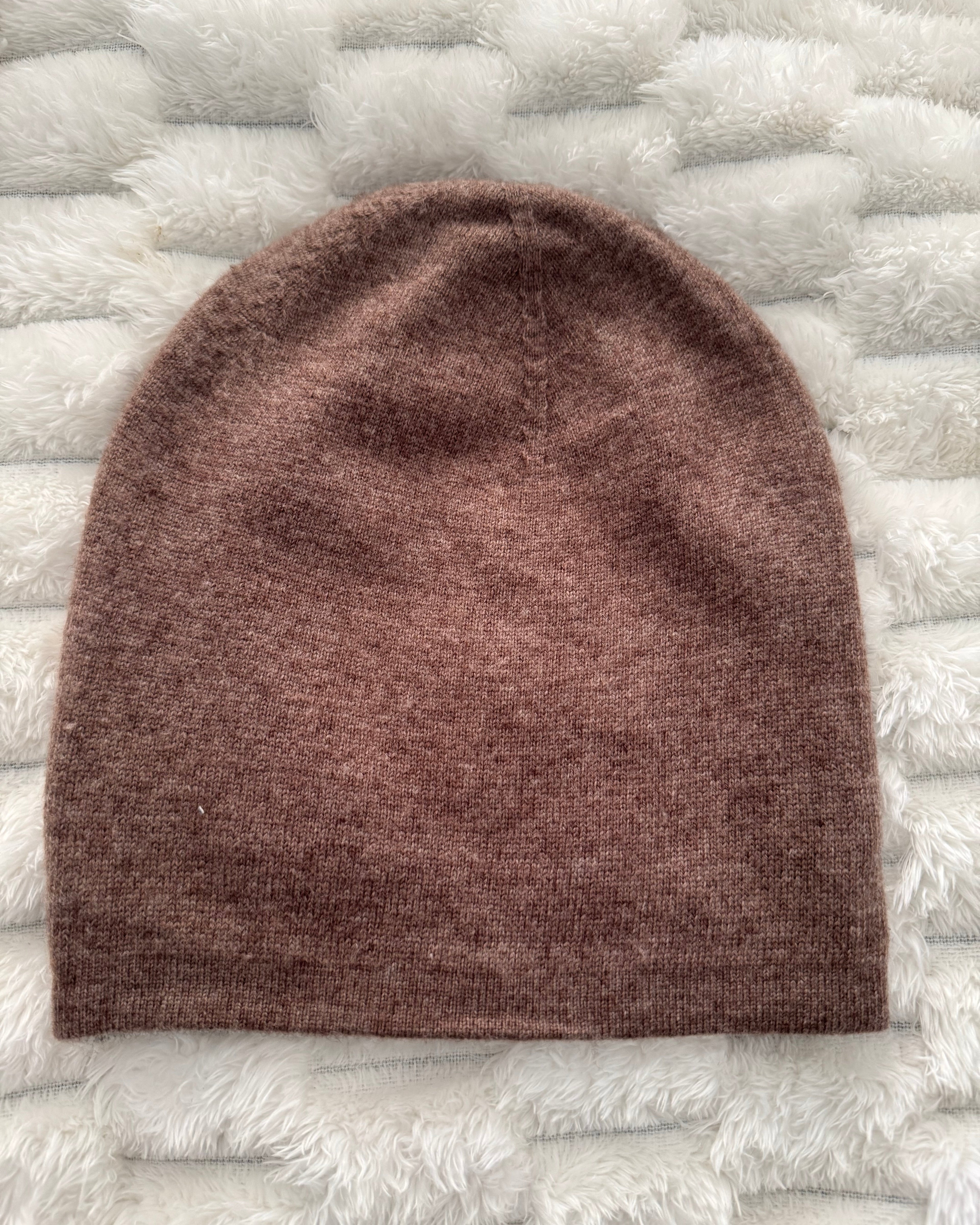 Brown knitted beanie on a textured white surface