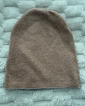 Brown knitted beanie on a textured gray surface