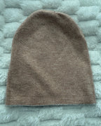 Brown knitted beanie on a textured gray surface