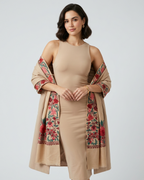 Woman wearing a beige dress with a floral embroidered shawl on a white background