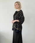 Woman wearing a black dress with a gold embroidered shawl against a white background