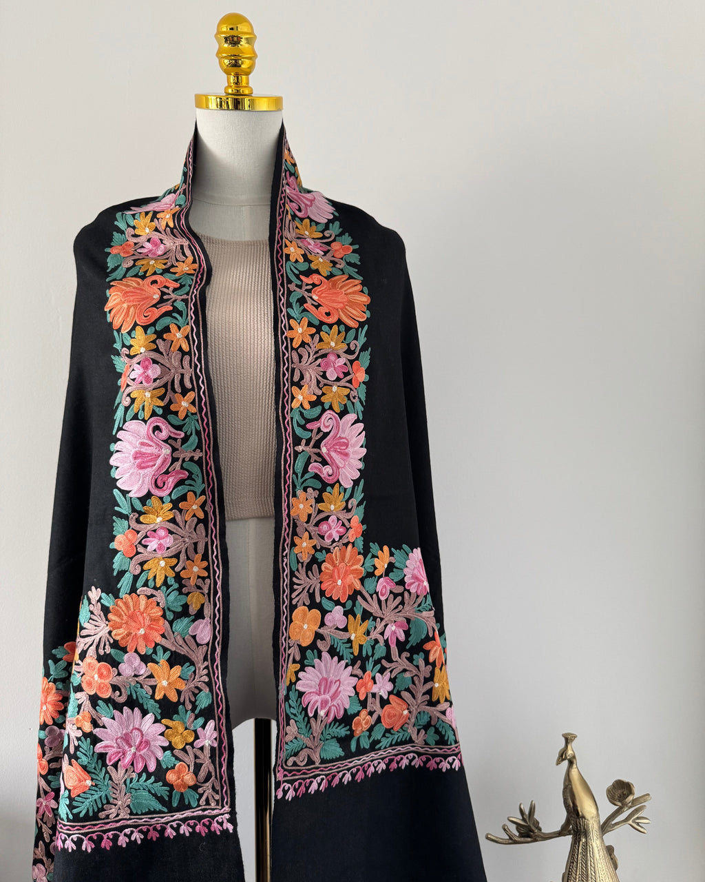 Decorative black shawl with floral embroidery on a white background