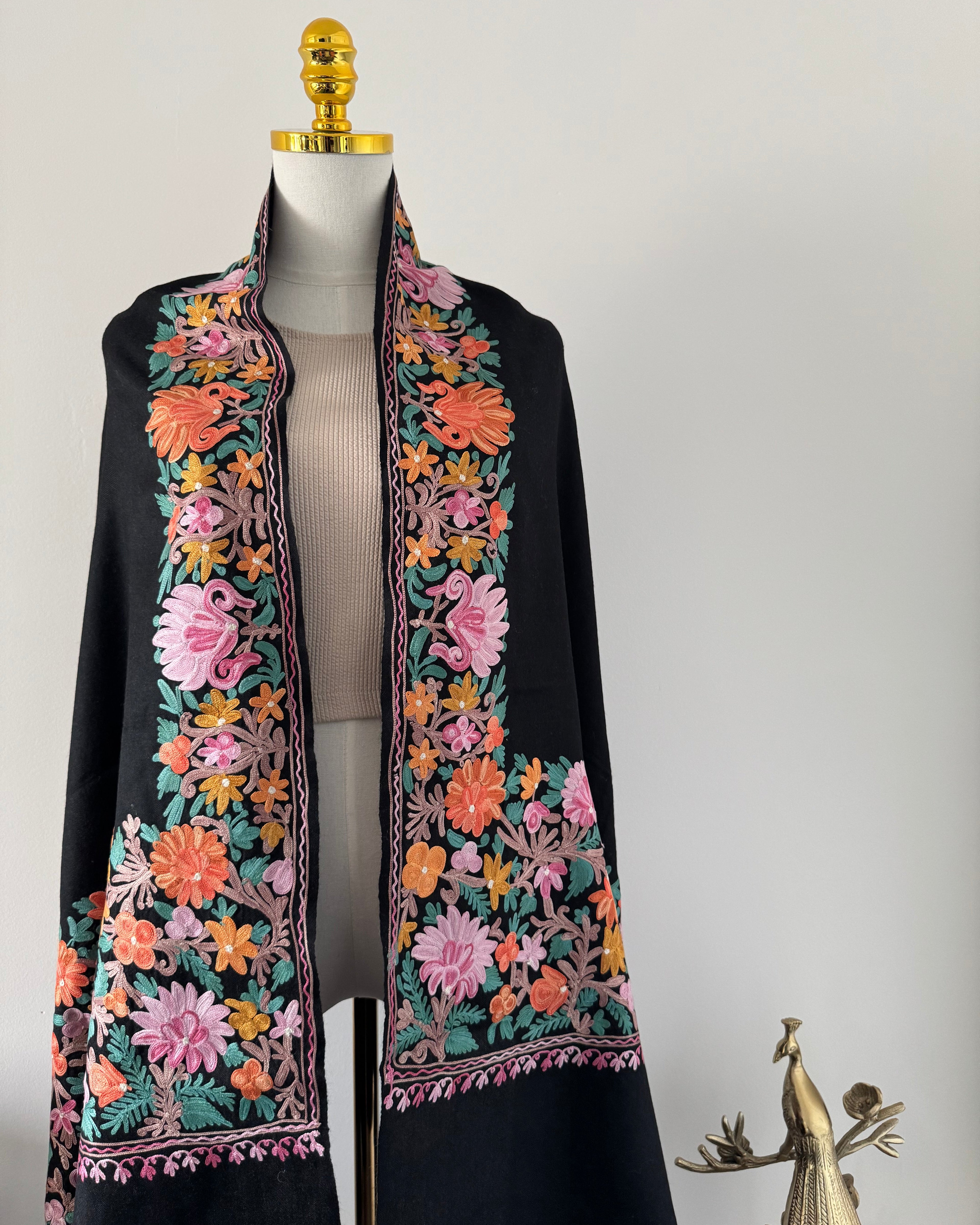 Decorative black shawl with floral embroidery on a white background