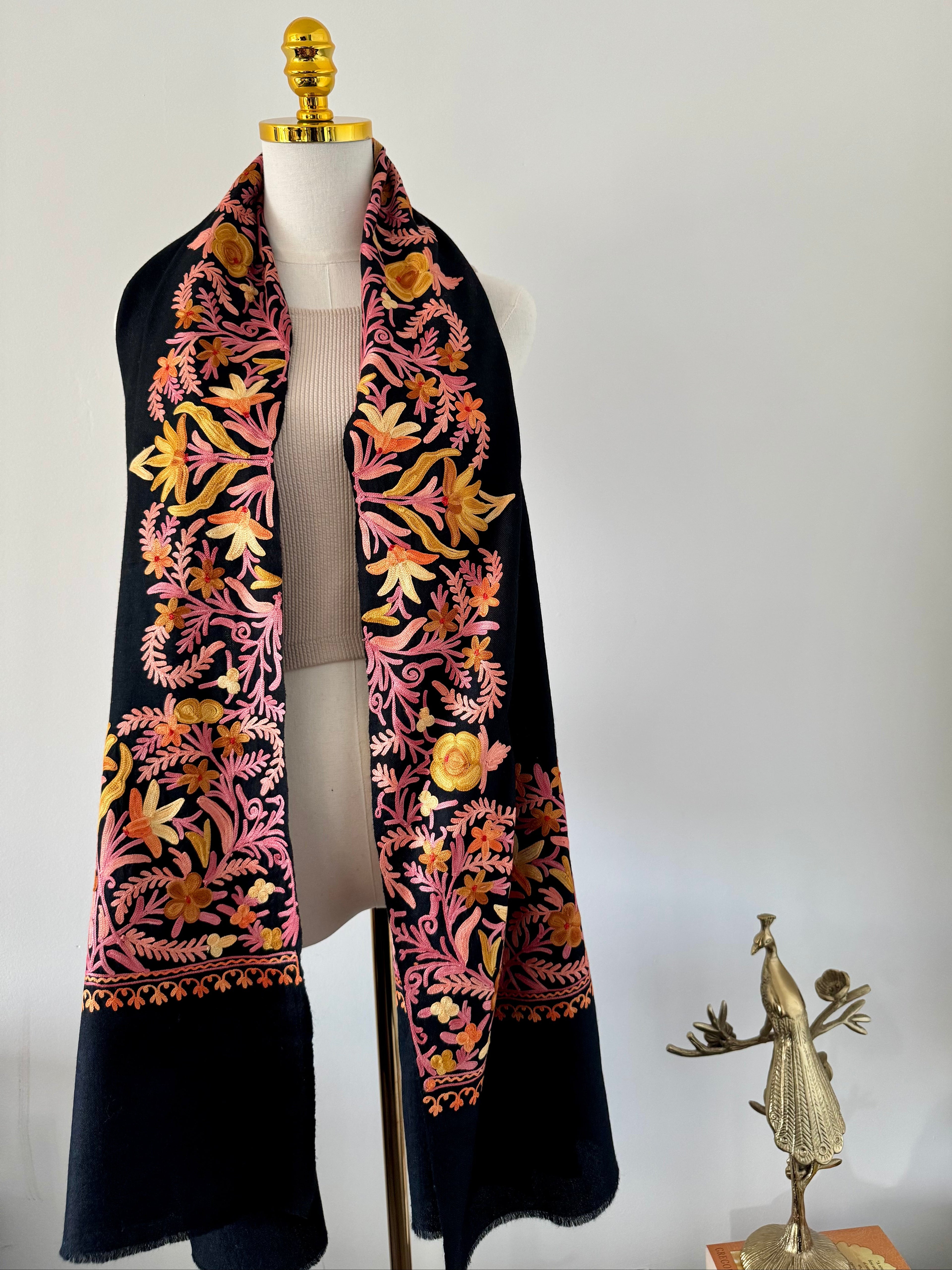 Black shawlwith floral patterns draped over a mannequin against a white background