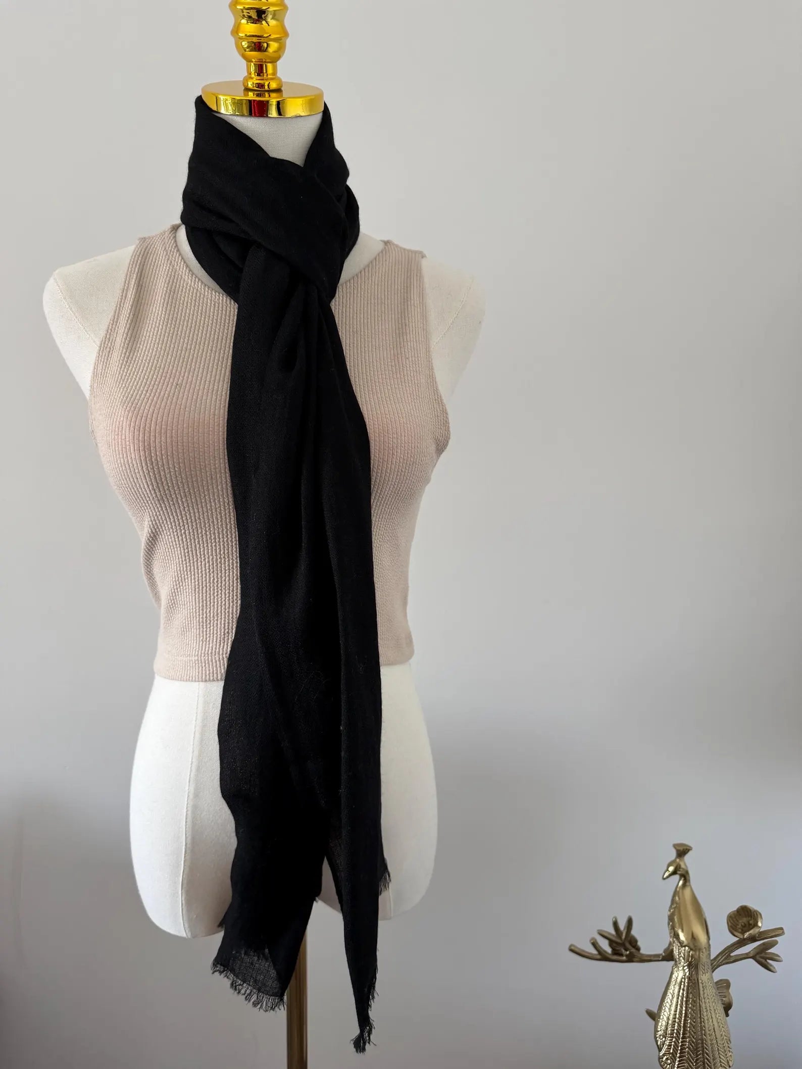 Black scarf draped over a mannequin bust against a plain background