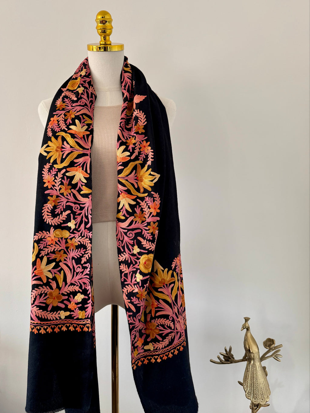 Black scarf with pink floral pattern on a mannequin against a plain background