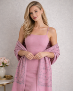 Woman wearing a pink dress with a matching shawl against a neutral background