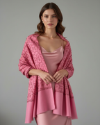 Woman wearing a pink shawl over a pink dress on a gray background