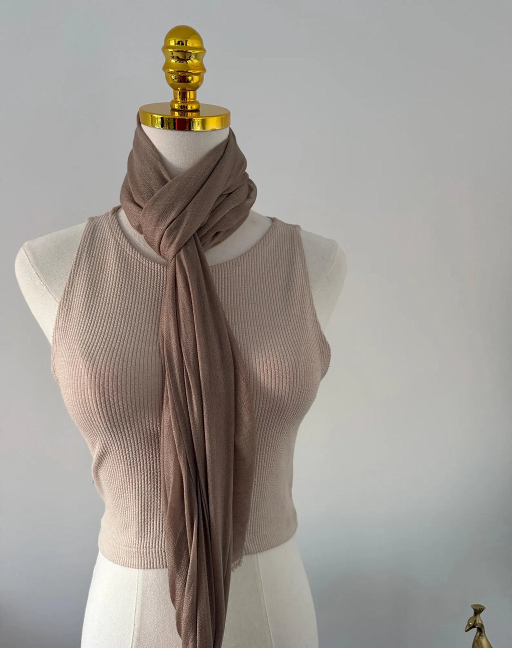 Mannequin wearing a beige ribbed tank top and brown scarf against a plain background