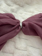 Close-up of a large purple bow on a textured white background