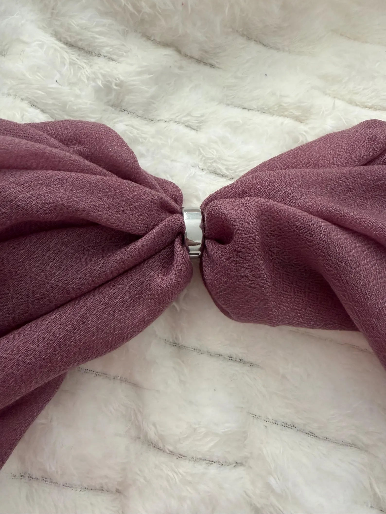 Close-up of a large purple bow on a textured white background