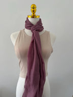 Mannequin wearing a beige top and purple scarf against a plain background