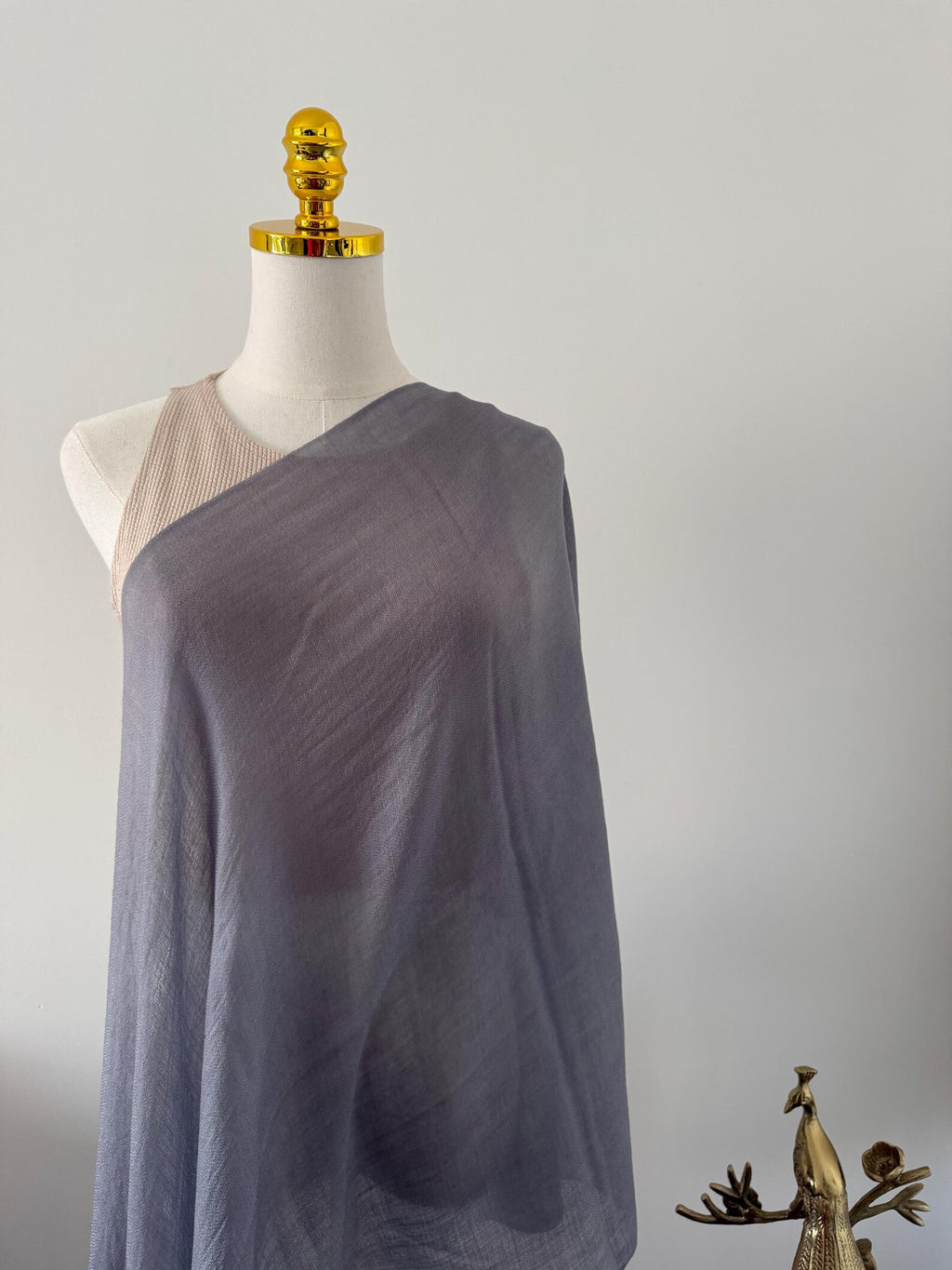 Mannequin wearing a draped gray fabric garment against a plain background