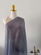 Mannequin wearing a draped gray fabric garment against a plain background