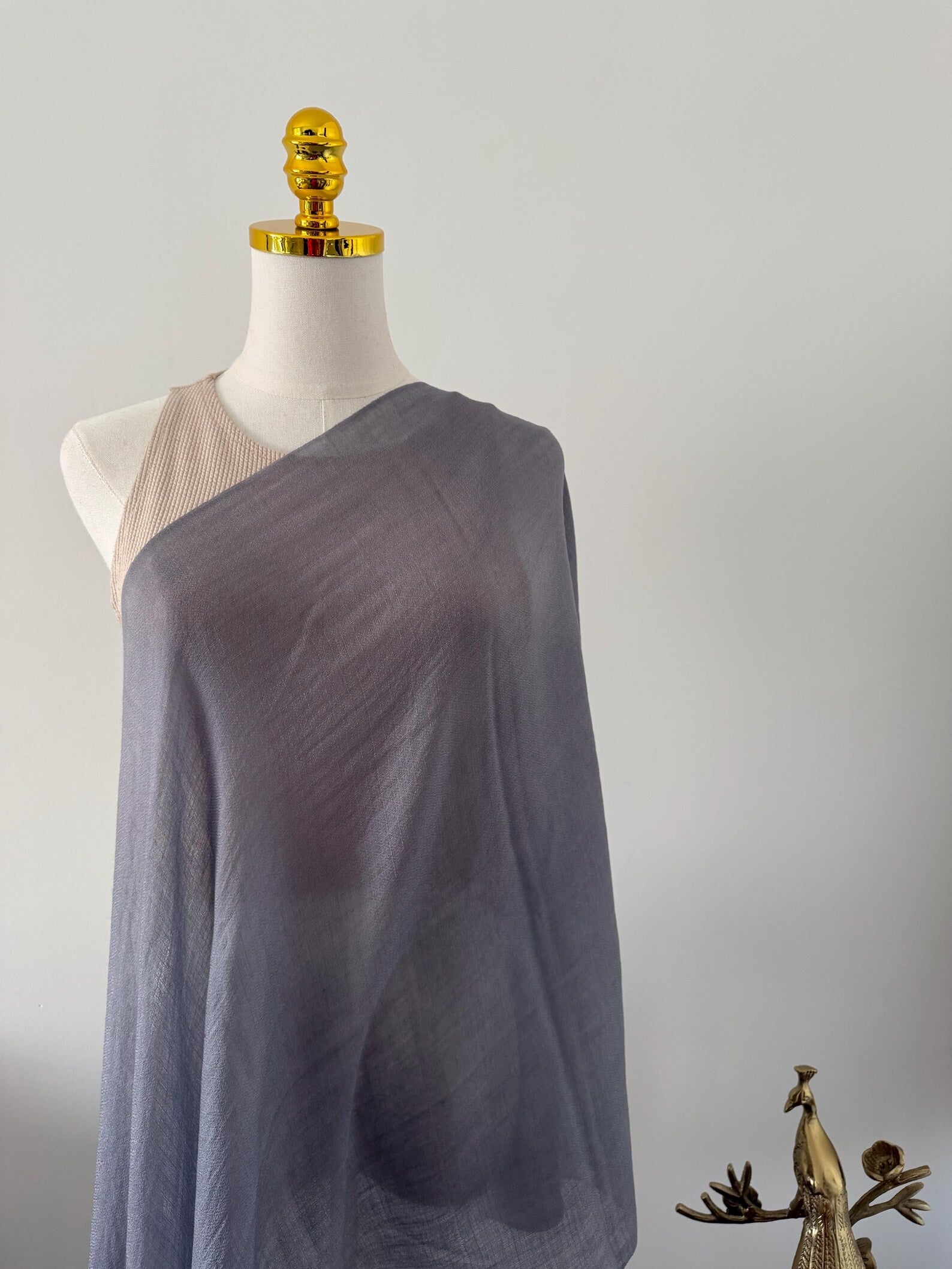 Mannequin wearing a draped gray fabric garment against a plain background